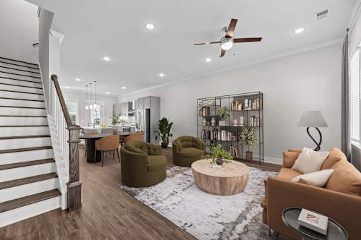 A living room with a staircase, a couch, a coffee table, and a bookshelf.