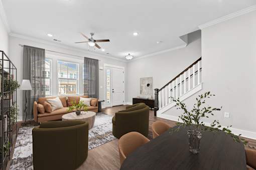 A living room with a brown sofa, a coffee table, and a staircase.