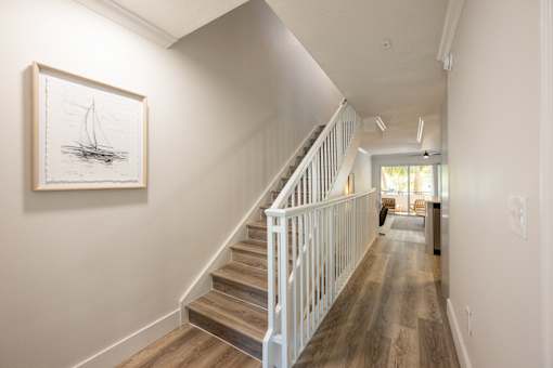 A drawing of a sailboat is hanging on a wall above a staircase.