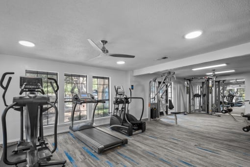 a gym with weights and cardio machines and a ceiling fan