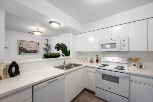 a kitchen with white appliances and white cabinets and a sink