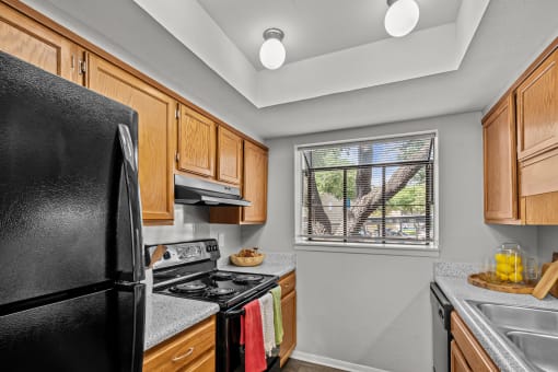 a kitchen with black appliances and wooden cabinets and a window