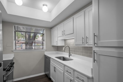 an empty kitchen with white cabinets and a window