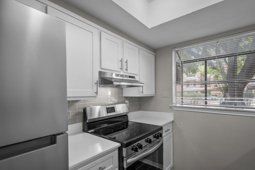 an empty kitchen with white cabinets and a window