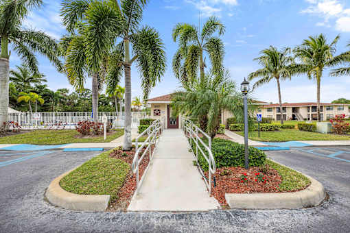 A building is surrounded by palm trees and a small garden.