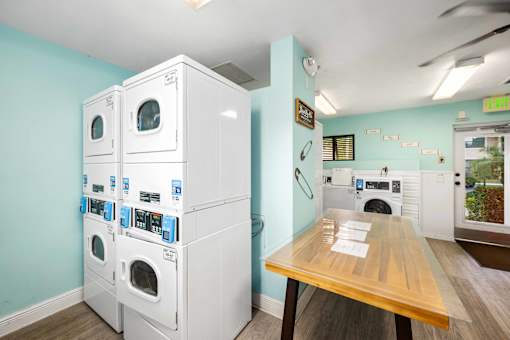 A laundry room with washers and dryers and a wooden table.