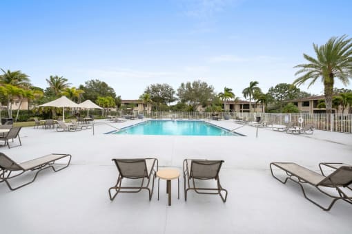 a swimming pool with lounge chairs and tables