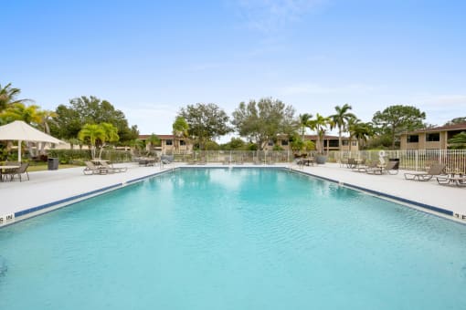 a large swimming pool with lounge chairs and umbrellas