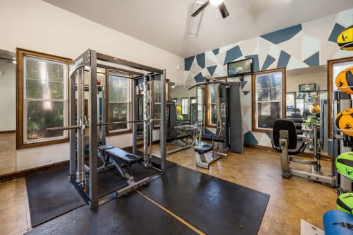A gym with a variety of equipment including a squat rack, bench, and weights.