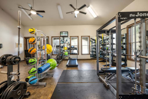 A gym with a variety of equipment including dumbbells, weight plates, and a bench press.