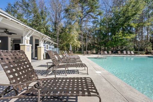 A pool area with chairs and a building in the background.