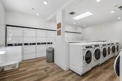 A row of white front load washing machines in a laundromat.