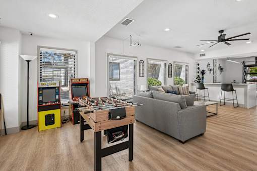 A living room with a grey couch, a wooden coffee table, and a yellow arcade machine.