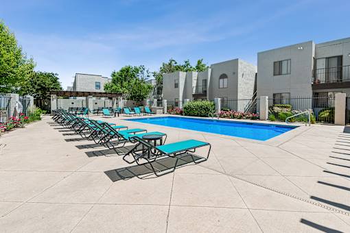 A swimming pool surrounded by lounge chairs and buildings.