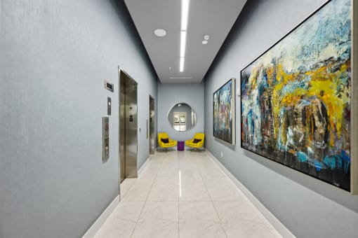 the hallway of a building with paintings on the wall and doors