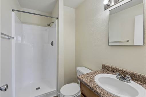 A bathroom with a toilet, sink, and shower.