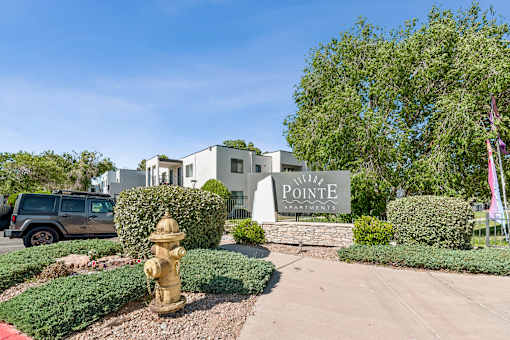 A sign that says Pointe Apartments is in front of a building.