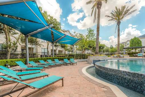 A pool area with sun loungers and a blue canopy.