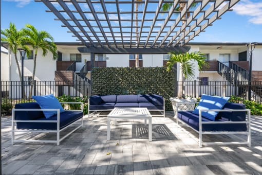 a patio with blue chairs and a table under a roof