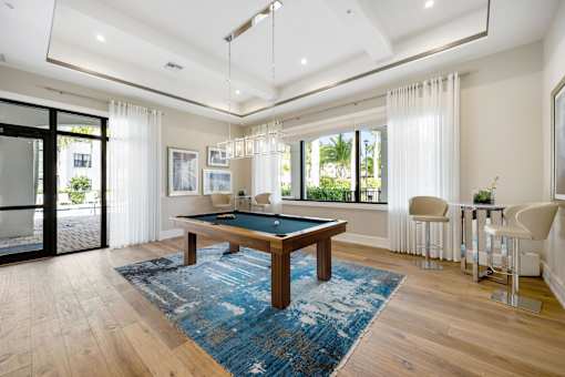 A room with a pool table and a bar area.