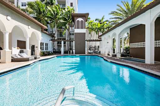 A swimming pool in a resort with a white building in the background.