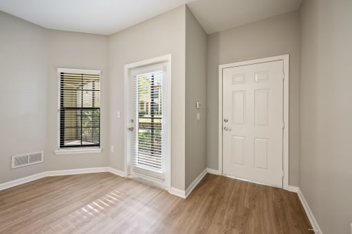 an empty living room with a white door and window