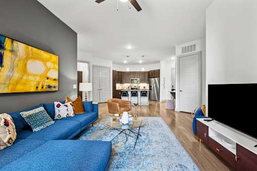 A living room with a blue couch and a painting on the wall.
