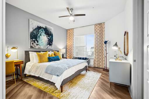 A bedroom with a bed, a desk, and a ceiling fan.