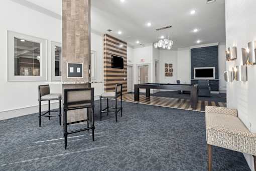A living room with a grey carpet and a black couch.