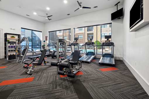 A gym with a variety of equipment including treadmills, weights, and exercise machines.