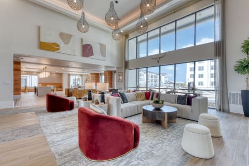 a living room with couches and chairs and large windows