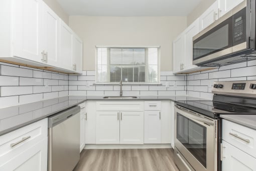 a kitchen with white cabinets and black appliances and a window