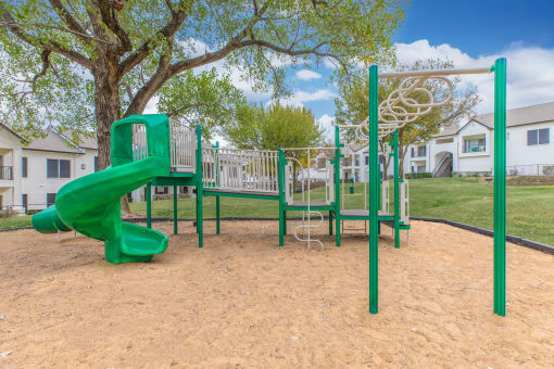 a playground with a slide and swings in a park