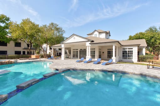 a large swimming pool with a house in the background