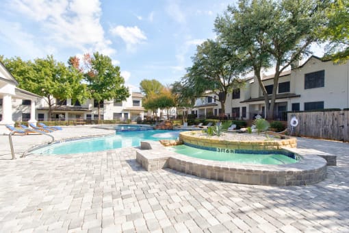 a swimming pool with a jacuzzi and a resort style pool with trees