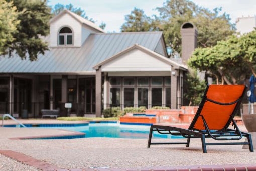 a pool chair in front of a house with a swimming pool