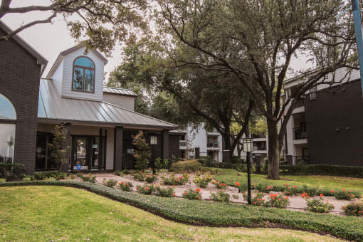a view of the front of a building with a garden and trees