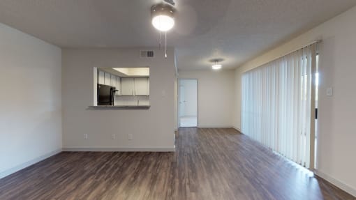 an empty living room with wood flooring and a large window