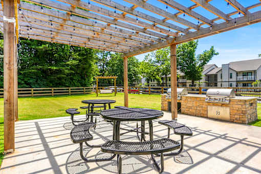 a patio with tables and chairs under a pergola