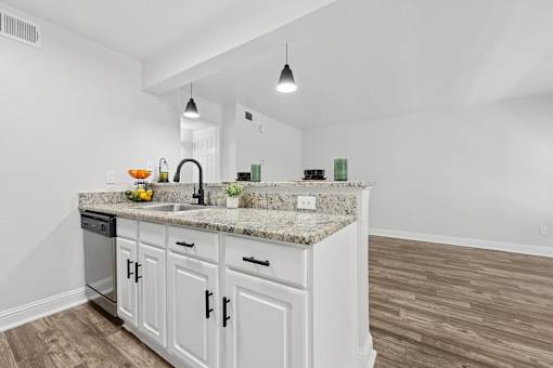 A kitchen with white cabinets and a granite countertop.