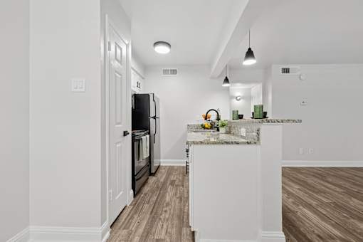 A kitchen with a black fridge and white cabinets.