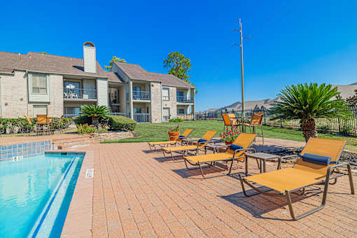 A poolside area with chairs and a building in the background.
