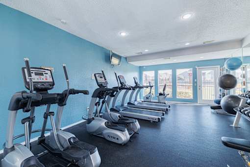 A gym with a row of treadmills and exercise balls.