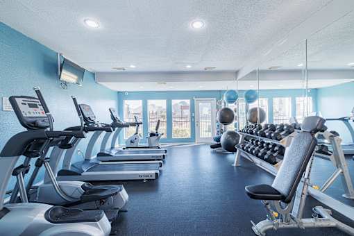 A gym with treadmills, exercise bikes, and dumbbells.