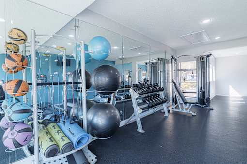 A gym with a variety of equipment including dumbbells, exercise balls, and resistance bands.