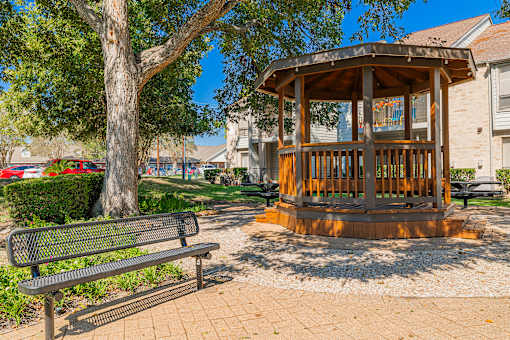 A wooden gazebo with a bench in front of it.