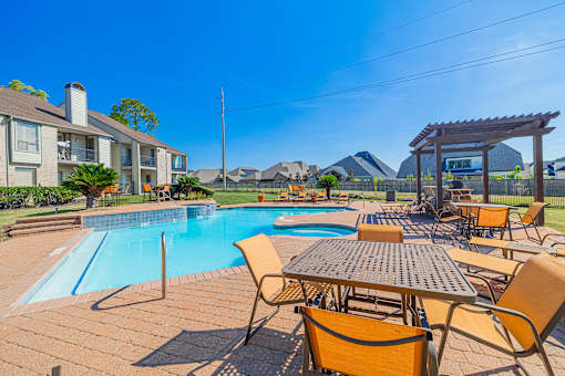 A poolside table and chairs are set up in front of a swimming pool.