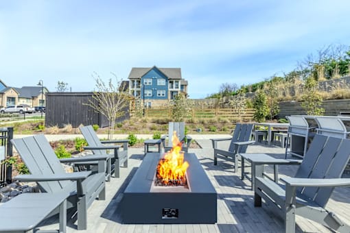A fire pit in the middle of a patio surrounded by chairs.