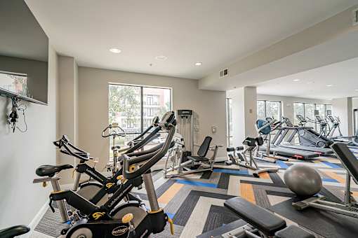 A gym with a variety of exercise equipment including treadmills, stationary bikes, and weight machines.