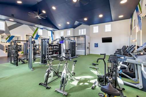 A gym with a variety of exercise equipment including treadmills, stationary bikes, and weight machines.